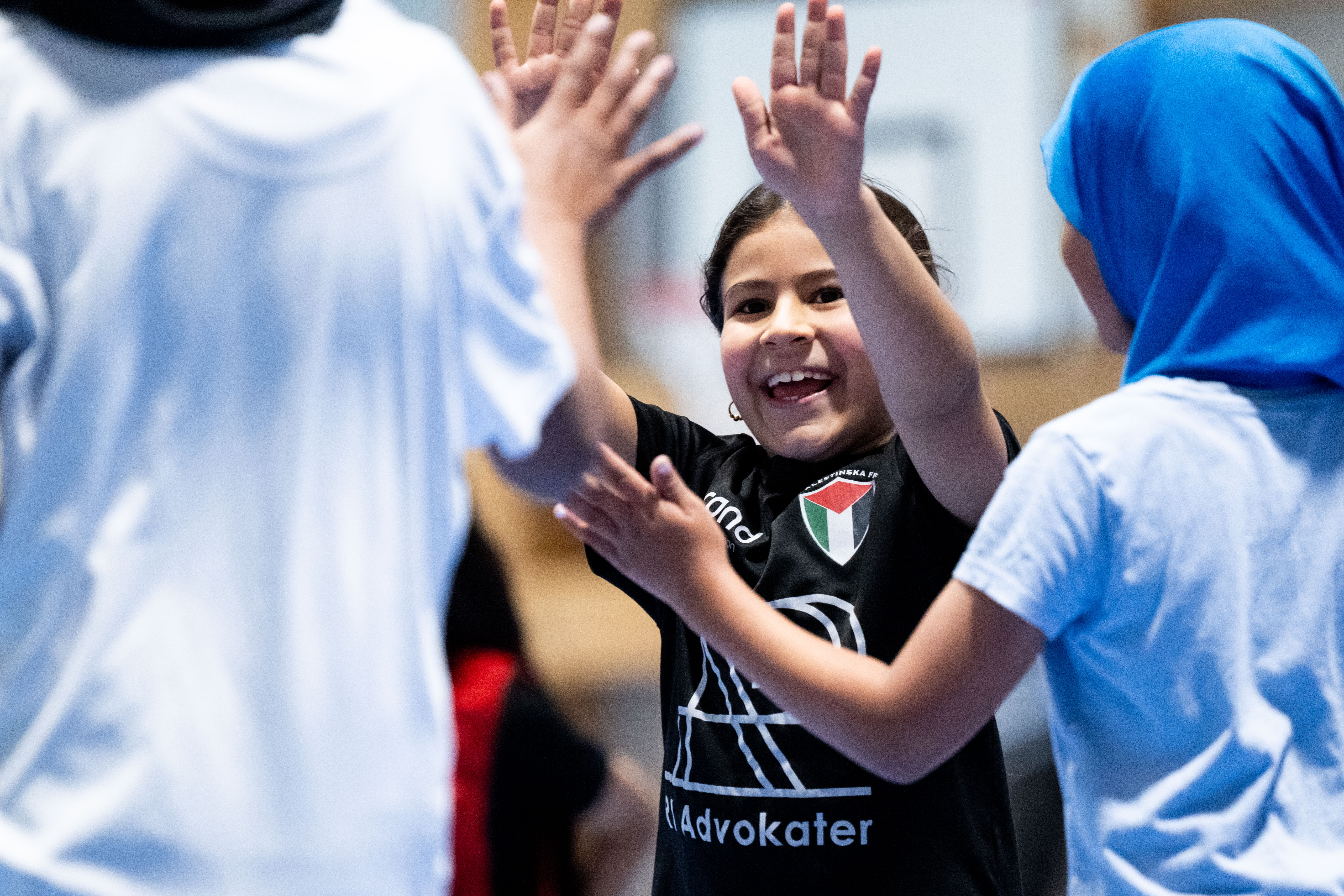 I en grupp av fotbollsspelande barn håller en pojke om en teddybjörn iförd matchtröja