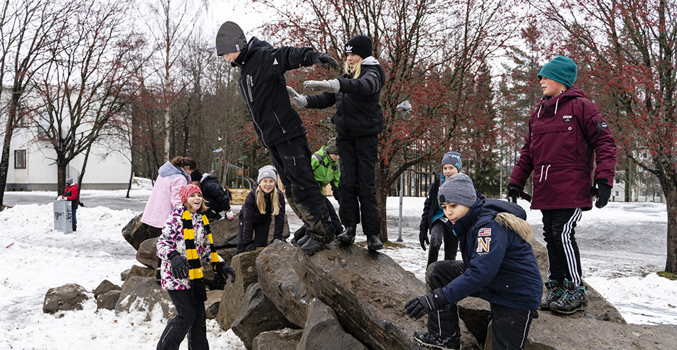 En grupp barn som leker på en hög med stenar på en skolgård