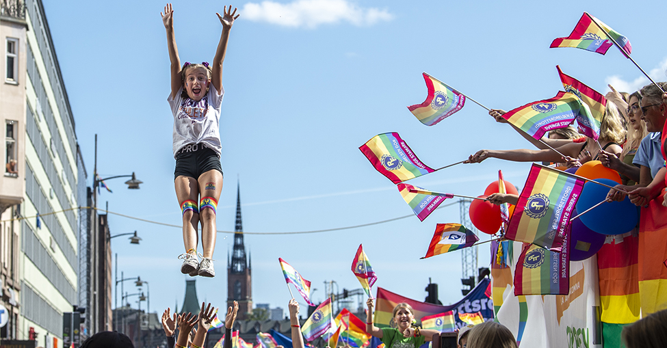Cheerleadinguppvisning på Prideparaden i Stockholm, med Riksidrottsförbundets flaggor på höger sida. 